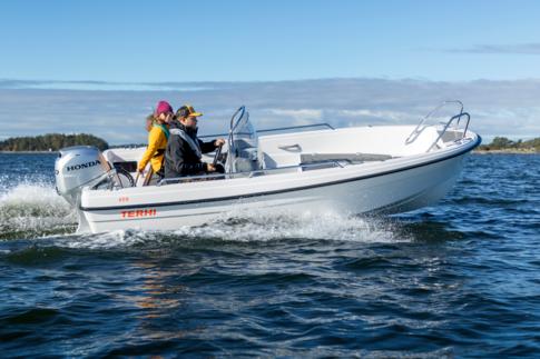 A man is driving a side console boat. A cheerful woman is sitting next to him on the bench.