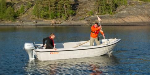 Two men are lowering fishing nets from the Terhi Nordic 6020 motorboat.