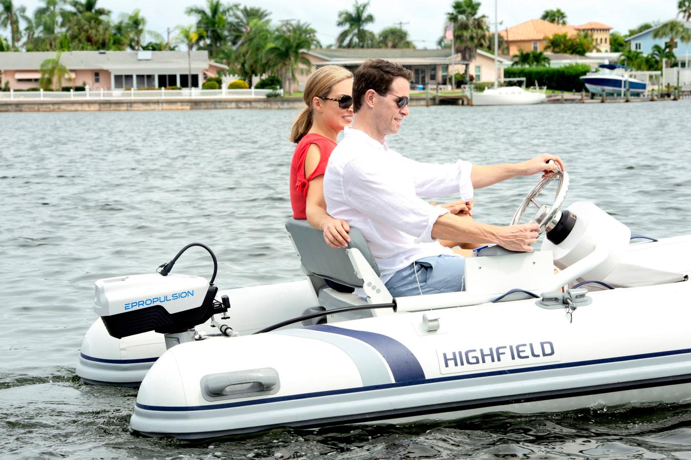 Pariskunta ajaa kesäisissä maisemissa pientä rattiohjattavaa kumivenettä, jossa on perässä ePropulsion-sähköperämoottori.