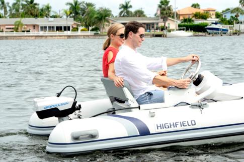 Pariskunta ajaa kesäisissä maisemissa pientä rattiohjattavaa kumivenettä, jossa on perässä ePropulsion-sähköperämoottori.